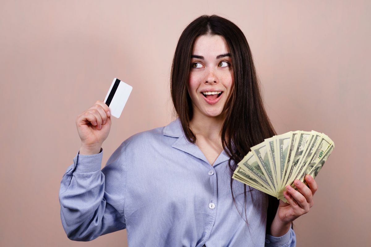 Electronic money vs cash. Young happy cheerful woman with credit card and dollar bills. Online payment, savings, financial concept